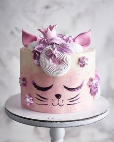 a cake decorated with pink and white frosting has a cat's face on it