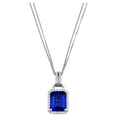 Elevate your elegance with this breathtaking 4.73 carat emerald-cut tanzanite pendant necklace, a statement of pure luxury and refined beauty. The vivid, deep blue-violet hue of the tanzanite is truly mesmerizing, drawing attention with its rich, vibrant color and impeccable clarity. Surrounding the centerpiece is a dazzling halo of round diamonds, meticulously set to enhance the brilliance of the tanzanite, creating a radiant frame that sparkles with every movement. This stunning pendant is set in lustrous 18 karat white gold, which complements the cool tones of the tanzanite and diamonds. The double cable chains add a contemporary twist, providing both strength and style, while perfectly balancing the grandeur of the pendant. Whether worn for a special occasion or to add a touch of luxur Luxury Diamond Necklace With Round Pendant And Cable Chain, Elegant Sapphire Necklace With Emerald Cut, Blue Emerald Cut Fine Jewelry Necklace, Blue Emerald Cut Necklace Fine Jewelry, Radiant Cut Tanzanite Jewelry For Formal Occasions, Formal Sapphire Necklace With Rectangular Shape, Formal Sapphire Baguette Cut Necklace, Sapphire Baguette Cut Necklace For Formal Occasions, Formal Sapphire Tanzanite Necklace