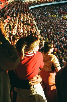 two people hugging each other in front of a large crowd at a sporting event,