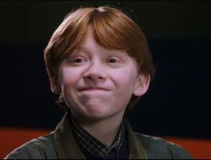 a young boy with red hair smiling at the camera