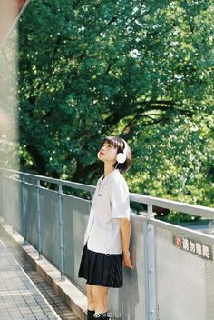 a girl standing on a bridge with headphones in her ears