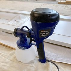 a blue and black blow dryer sitting on top of a white sheeted floor