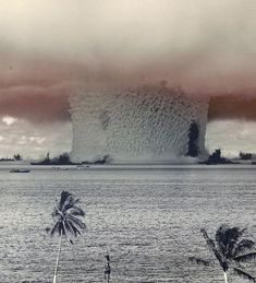 an old photo of a huge mushroom cloud in the sky over water and palm trees