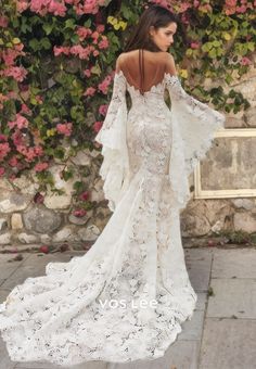 the back of a woman's wedding dress in front of a wall with flowers