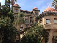 a large building with many windows and balconies on the top floor, surrounded by palm trees