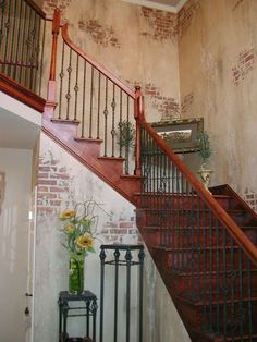 a wooden staircase with wrought iron railings and flowers in a vase on the side