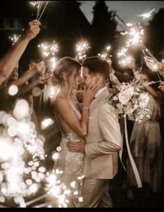 a bride and groom kissing while surrounded by sparklers