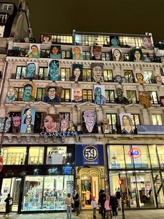 a large building with many windows and people walking by it at night in the city