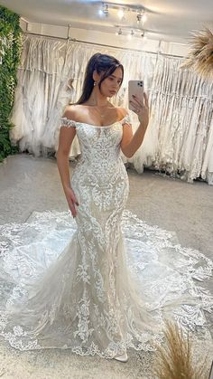 a woman taking a selfie in front of a mirror wearing a white wedding dress