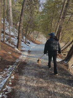 a woman walking her dog on a snowy path in the woods with no one around