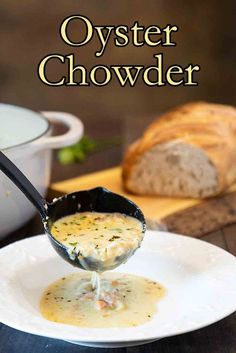 a spoon full of oyster chowder on top of a white plate with bread in the background