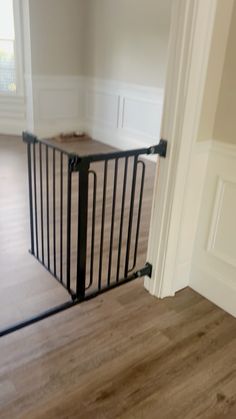 an empty room with wooden floors and a black gate