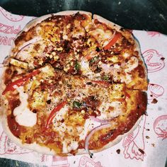 a pizza sitting on top of a table covered in cheese and toppings with red onions