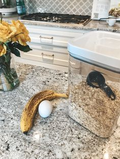 a banana and some rice in a glass jar on a kitchen counter with yellow flowers