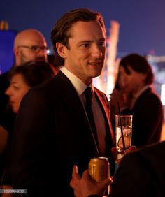 a man in a suit and tie holding a drink