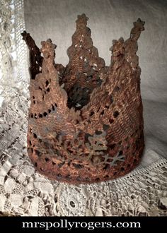 a crocheted crown sitting on top of a lace covered tablecloth next to a window