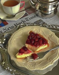 a piece of cheesecake on a plate with raspberry sauce and a cup of tea