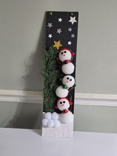 three snowmen are standing in front of a christmas tree on a black and white board