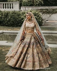 a woman in a bridal gown standing on the grass with her hands behind her head