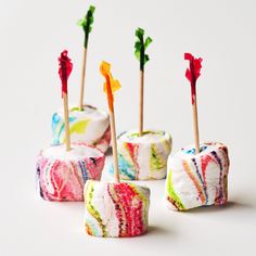 marbled marshmallows with toothpicks in them on a white surface