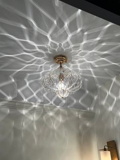 a chandelier hanging from the ceiling in a room with light streaming through it