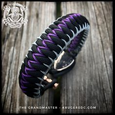 the purple and black paracorine bracelet is on top of a wooden table