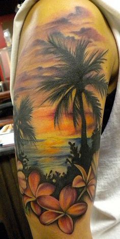 a man with a palm tree and flowers tattoo on his arm is standing in front of the ocean