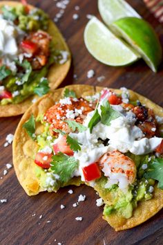 two tortillas topped with shrimp, tomatoes and lettuce on a wooden table