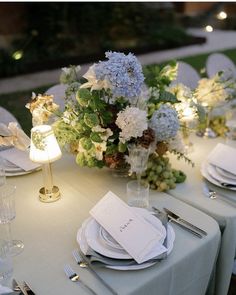 the table is set with place settings and flowers in vases on top of plates