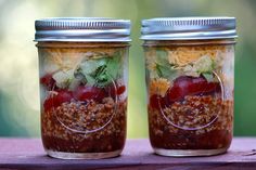 two jars filled with food sitting on top of a wooden table