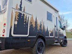 a camper van with trees painted on the side