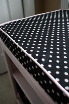 a black and white polka dot covered table with drawers in the background, next to a door