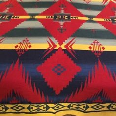 a red, yellow and blue blanket sitting on top of a bed