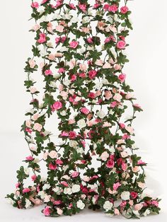 an arrangement of pink and white flowers with green leaves on the top, in front of a white background