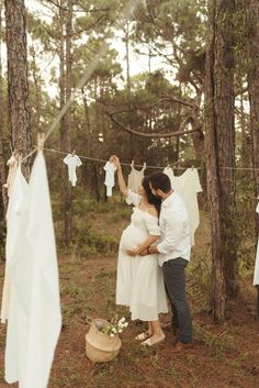 a man and woman standing next to each other in front of clothes hanging on a line