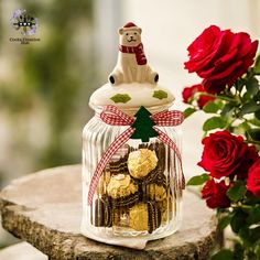 a glass jar filled with chocolates next to a bouquet of red roses and a teddy bear figurine