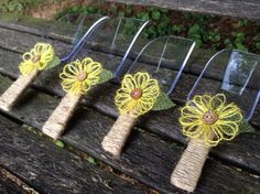 four small yellow flowers are sitting on top of a wooden bench, with wire attached to them