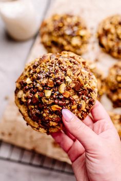 a person holding up a cookie with nuts on it