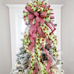 a christmas tree decorated with green and red polka dot bow, pine cones and ribbon