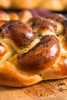 a hot cross bread sitting on top of a wooden cutting board next to buns