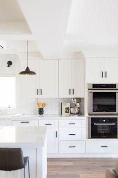 a kitchen with white cabinets and an oven in the center, along with bar stools