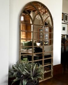 a large arched window in the middle of a living room next to a potted plant