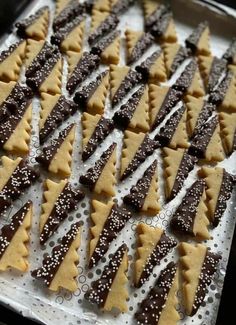 christmas tree shaped cookies on a baking sheet lined with white and brown sprinkles