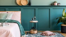 a bedroom with green walls and pink bedding in the corner, potted plant next to it