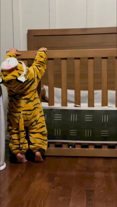 a person in a tiger costume standing next to a crib