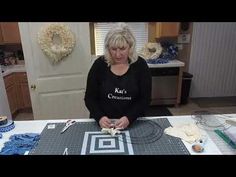 a woman standing in front of a table with some scissors and yarn on top of it