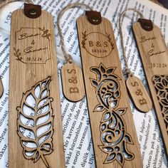 three wooden bookmarks with engraved designs on them sitting on top of an open book