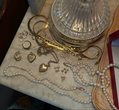 a table topped with lots of jewelry and a glass bowl on top of the table