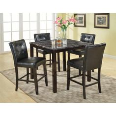 a dining room table with four chairs and a vase