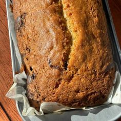 a loaf of banana bread sitting on top of a pan with wax paper around it